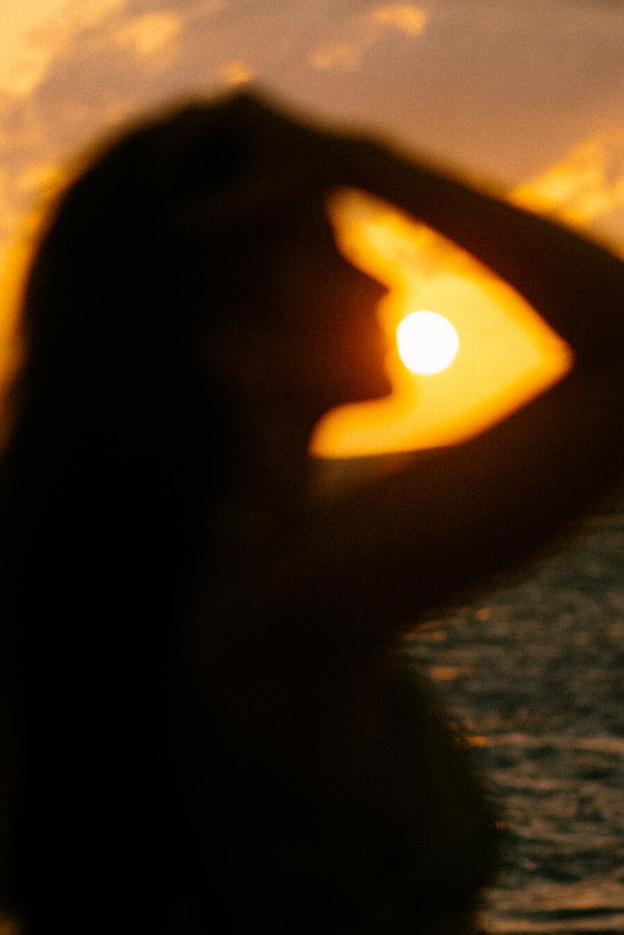The sun caught in the crook of her raised arm.